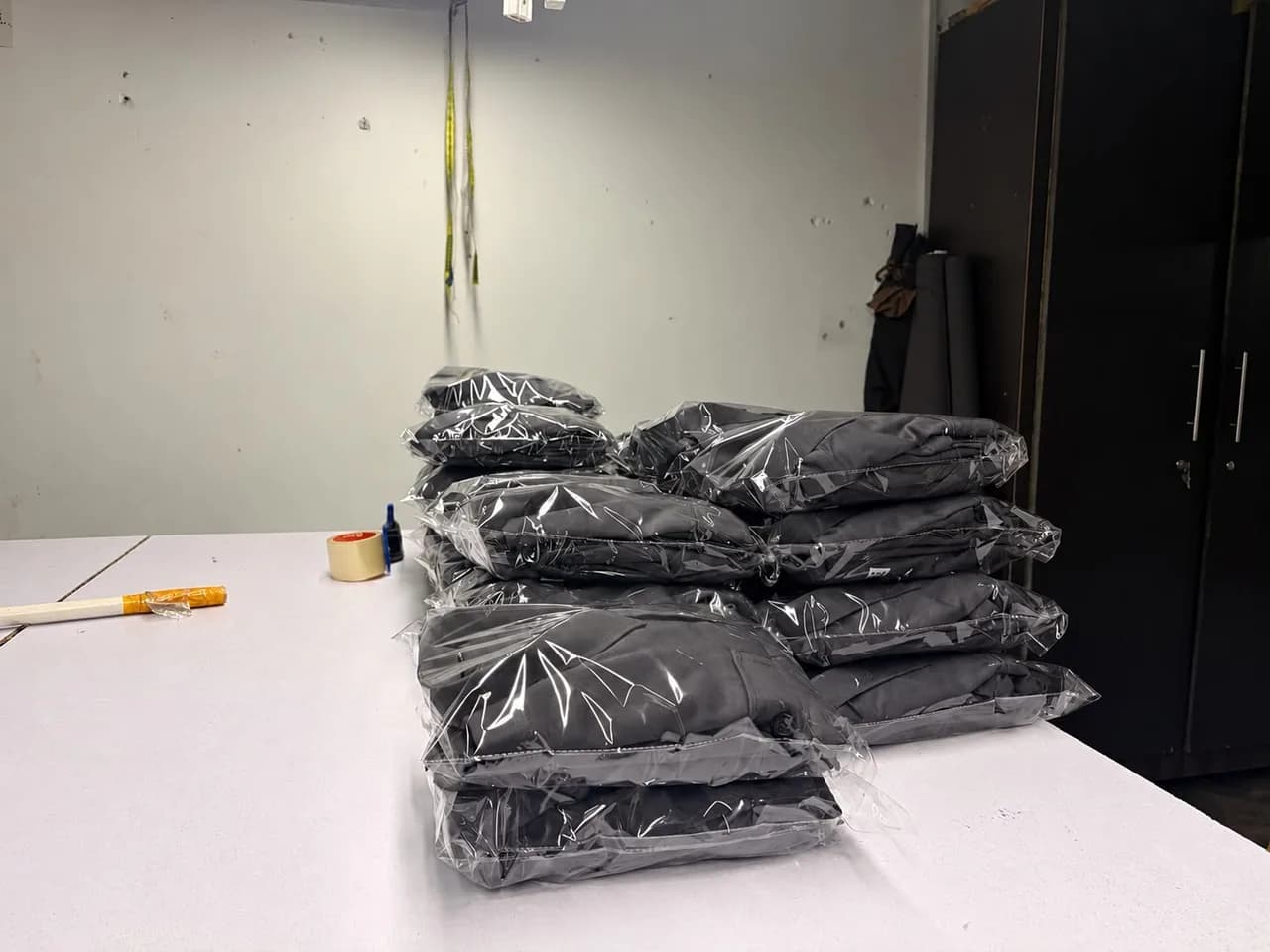 Finished workwear garments individually sealed in polybags and stacked in size order on the finishing table at the KBwear factory in Lahore