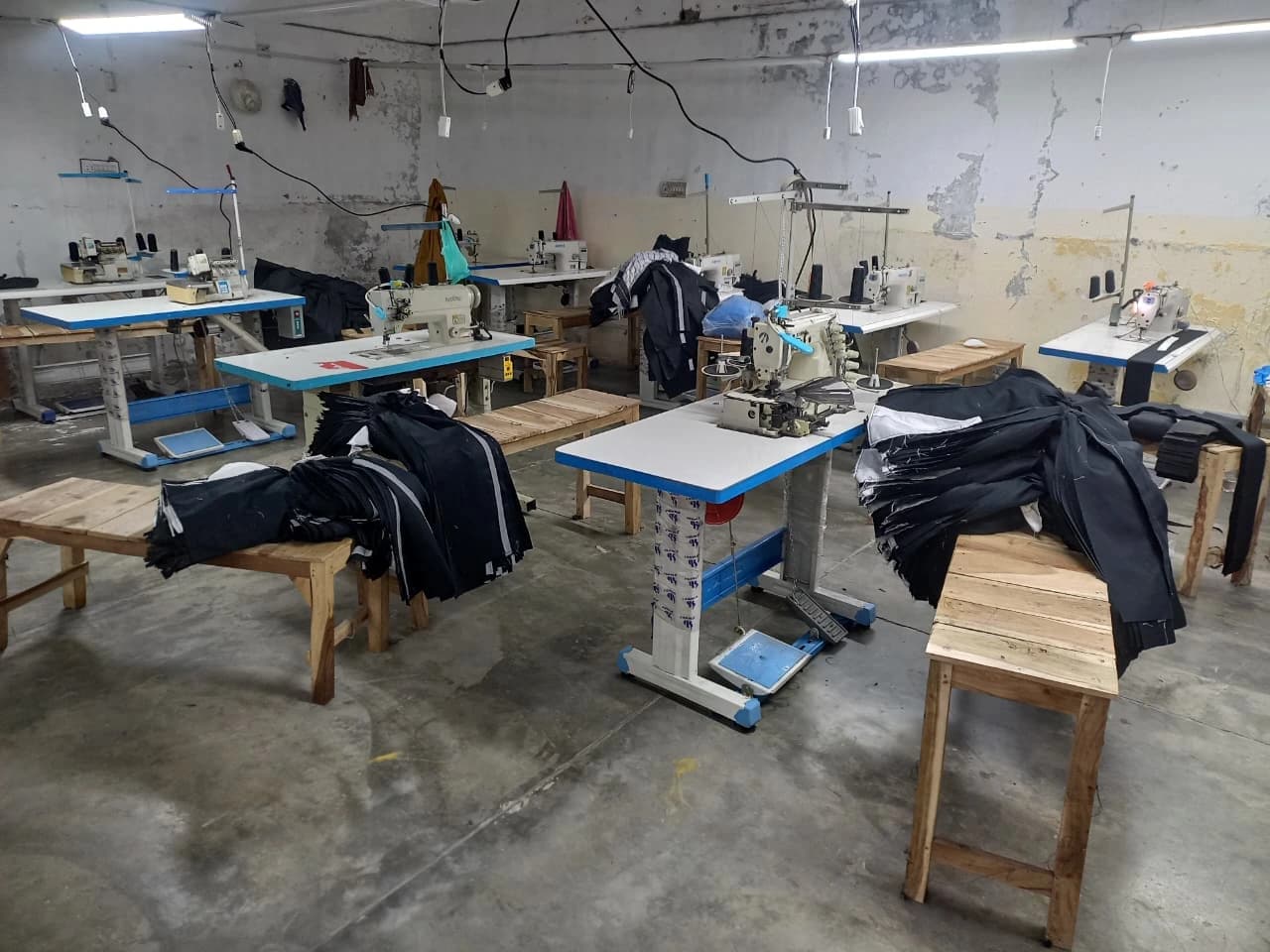 Wider view of the KBwear stitching floor in Lahore showing overlock, lockstitch and flatlock machines with work in progress