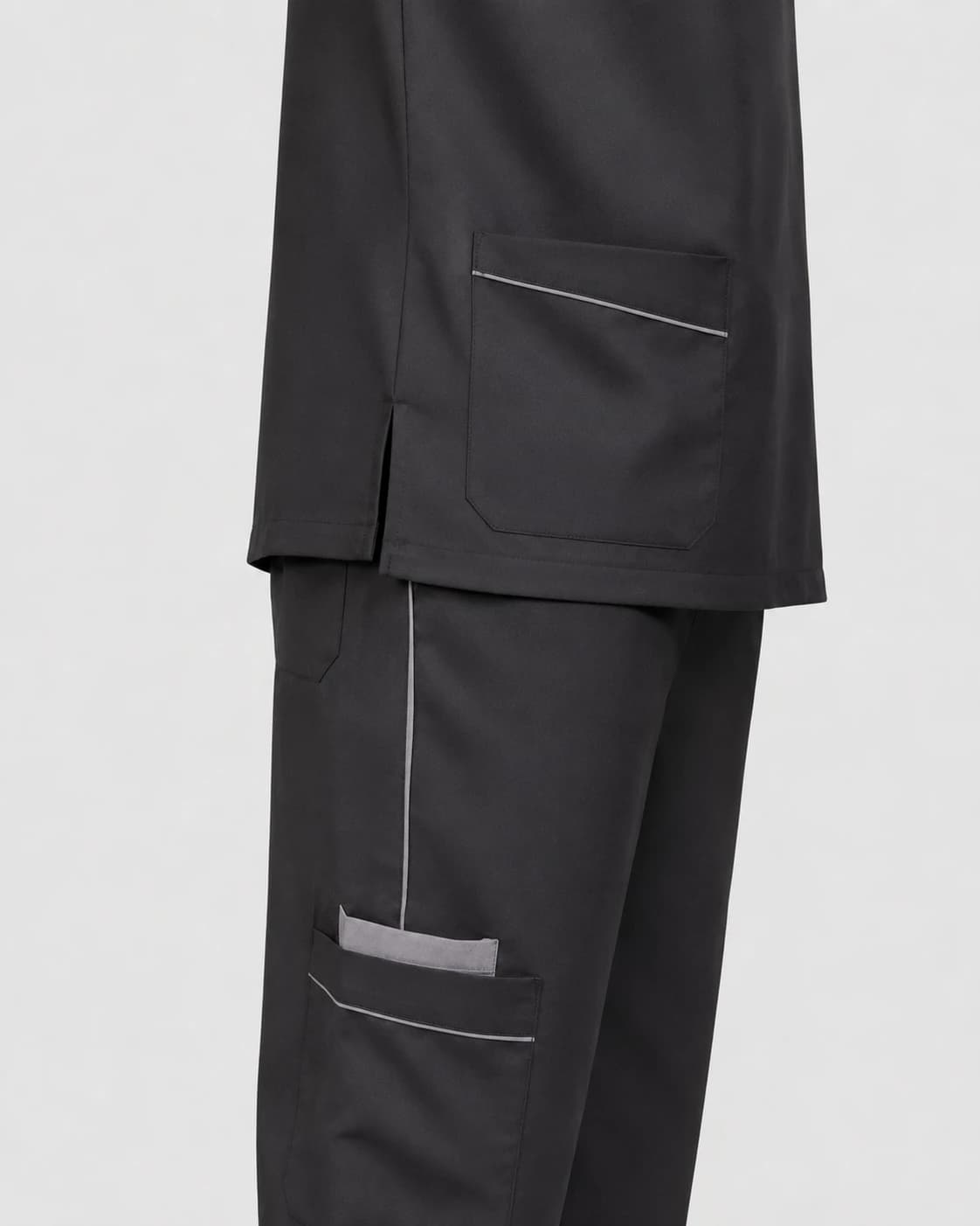 Close-up of a KBwear charcoal scrub set showing the piped hip pocket, side vent and trouser cargo pocket